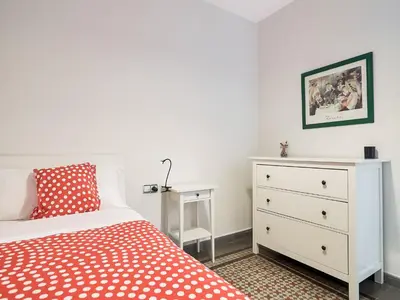 a bedroom with a bed and a dresser with a red blanket at Belvilla by OYO Rambla Paris Apartment in Barcelona