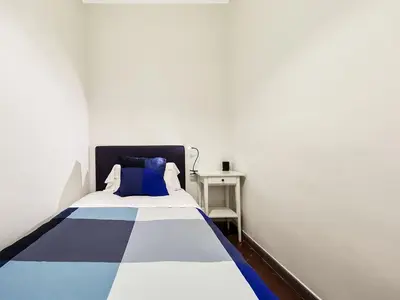 a bedroom with a bed with blue and white sheets at Belvilla by OYO Rambla Paris Apartment in Barcelona