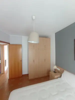 a bedroom with a bed and a cabinet and a lamp at Apartamento, 3° línea de playa in Cubelles