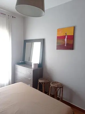 a bedroom with a bed and a mirror and two stools at Apartamento, 3° línea de playa in Cubelles