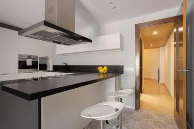 a kitchen with a black counter and two stools at Sunny Beachside Haven 2 BD in the Marina District in Barcelona