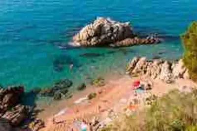 a view of a beach with rocks and the ocean at Apartamento “La Caleta” in Calella