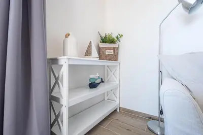 a white shelf in a bedroom next to a bed at Hauzify I Apartaments Can Pi in San Pol de Mar