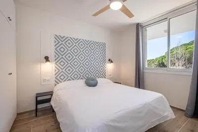 a bedroom with a white bed and a window at Hauzify I Apartaments Can Pi in San Pol de Mar