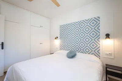 a bedroom with a white bed and a geometric accent wall at Hauzify I Apartaments Can Pi in San Pol de Mar