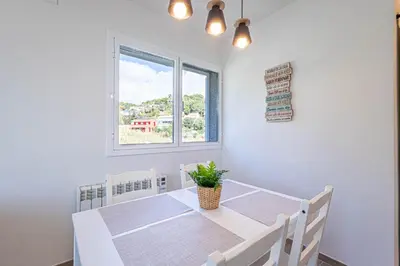 a dining room with a white table and a window at Hauzify I Apartaments Can Pi in San Pol de Mar
