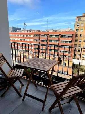 a wooden table and two chairs on a balcony at +25Y ONLY, Family flat near the beach in Barcelona