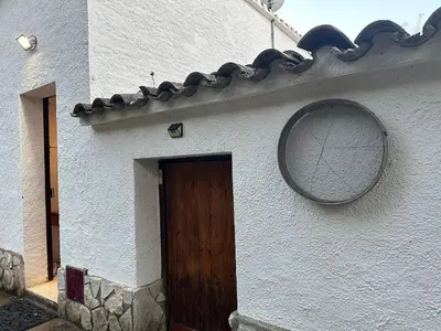 a white building with a wooden door and a mirror at Can Ginesta Muy feliz&tranquilo in Barcelona
