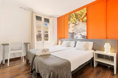 a bedroom with two beds and an orange wall at AB Vila i Vila Apartments in Barcelona