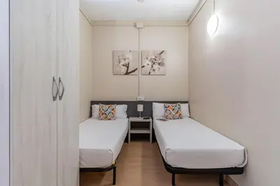 two beds in a small room with a table at AB Vila i Vila Apartments in Barcelona