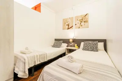 two beds in a room with white walls at AB Vila i Vila Apartments in Barcelona