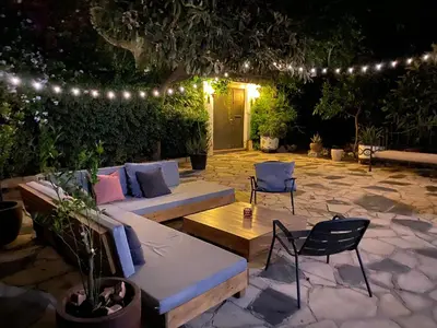 a patio with a couch and chairs and lights at Ca l'Andreu Teià. Casa modernista in Teià