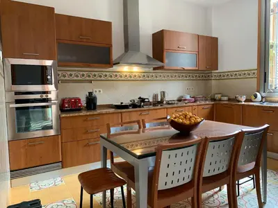 a kitchen with a table and chairs and a kitchen with a stove at Ca l'Andreu Teià. Casa modernista in Teià