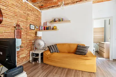 an orange couch in a living room with a brick wall at Beachside Bliss Charming 1-bedroom, Barceloneta in Barcelona