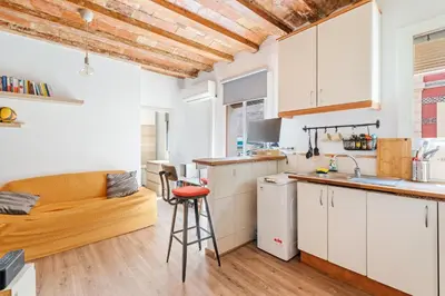 a kitchen with white cabinets and a couch in a room at Beachside Bliss Charming 1-bedroom, Barceloneta in Barcelona