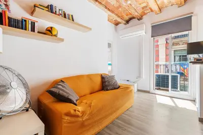 an orange couch in a living room with a window at Beachside Bliss Charming 1-bedroom, Barceloneta in Barcelona
