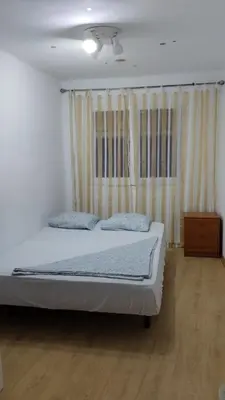 a bedroom with a bed and a wooden floor at metro La Salut in Badalona