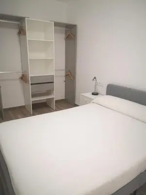 a bedroom with a large white bed and shelves at Apartament LA SAL in Pineda de Mar