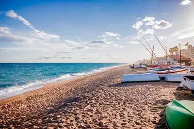 a beach with boats on the sand and the ocean at L'Hostalet GuestHouse in Pineda de Mar