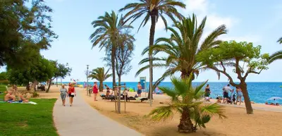 people walking on a beach with palm trees and the ocean at L'Hostalet GuestHouse in Pineda de Mar