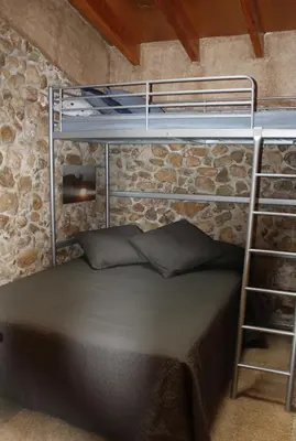 a bedroom with bunk beds in a stone wall at Masia Cal Sisplau, con piscina y rodeada de viñedos a 10 minutos de Vilafranca del Penedés, Barcelona ,Cataluña in San Martín Sarroca