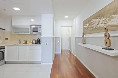 a kitchen with white cabinets and a wooden floor at Ola Living Plaza Catalunya in Barcelona