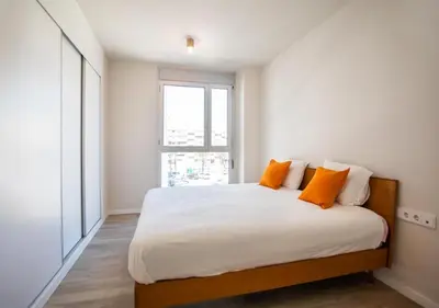 a bedroom with a bed with orange pillows and a window at Forum Casa Barcelona in Sant Adria de Besos