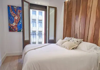 a bedroom with a white bed with a large window at Stay U-nique Apartment Padilla in Barcelona