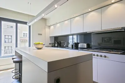 a kitchen with white cabinets and a bowl of fruit on a counter at Ola Living Paseo de Gracia in Barcelona