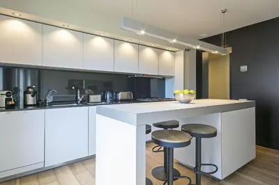 a kitchen with white cabinets and bar stools at Ola Living Paseo de Gracia in Barcelona
