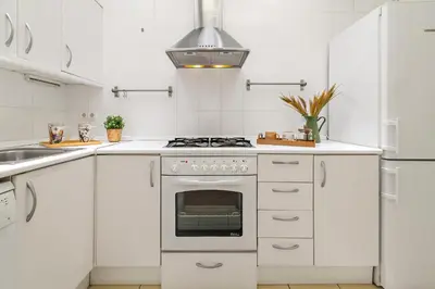 a white kitchen with a stove and a sink at Tendency Apartments Sagrada Familia Penthouse in Barcelona