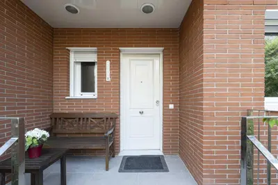 a brick house with a white door and a bench at Apartamento Luxury Gran Via 2 in Hospitalet de Llobregat