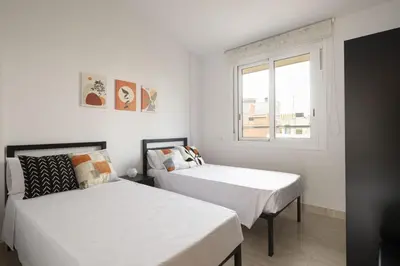 two beds in a white room with a window at Apartamento Luxury Gran Via 2 in Hospitalet de Llobregat