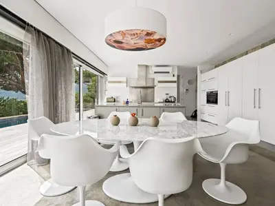 a white kitchen with a table and white chairs at Design villa sea views and lap pool in Cabrils