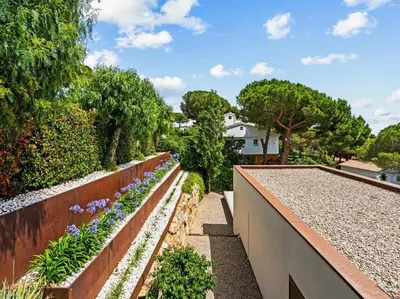 a garden with a retaining wall and flowers at Design villa sea views and lap pool in Cabrils