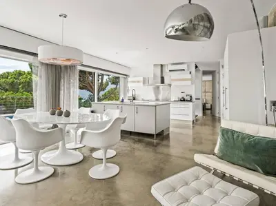 a kitchen and living room with a table and chairs at Design villa sea views and lap pool in Cabrils