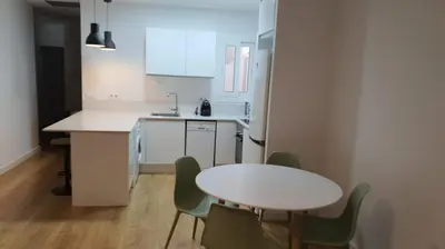a kitchen with a white table and chairs and a table at Gaudi Street Apartments in Sitges