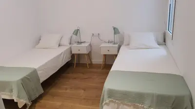 two beds in a room with two tables and a window at Gaudi Street Apartments in Sitges