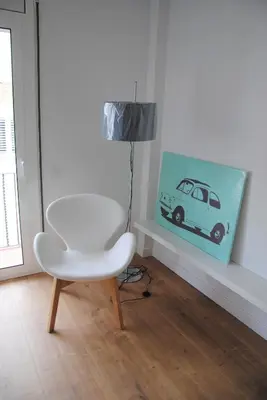a white chair in a room with a picture of a car at Gaudi Street Apartments in Sitges