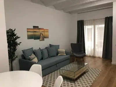 a living room with a blue couch and a table at Gaudi Street Apartments in Sitges