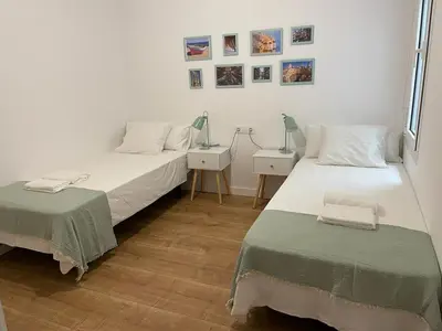 a bedroom with two beds and a table with a lamp at Gaudi Street Apartments in Sitges