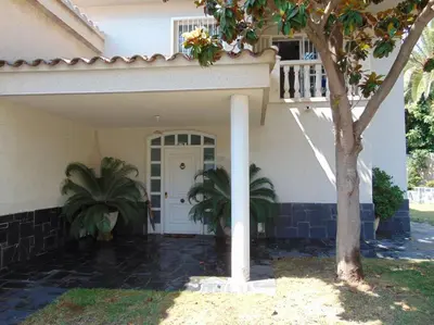 a house with a white door and a tree at Basketball court, pool, BBQ, gardens, seaviews in San Pol de Mar