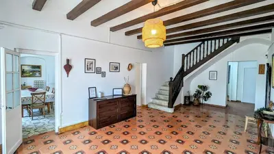 a large living room with a staircase and a table at Historic house 5 minutes walk from the beach in San Pol de Mar