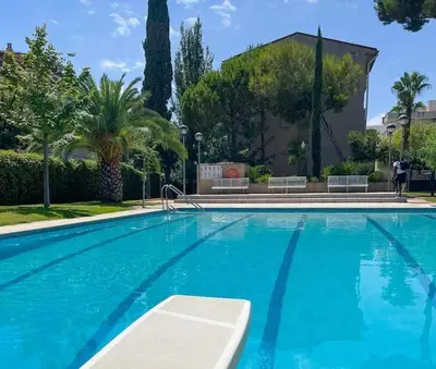 a large blue swimming pool with trees and a building at Apartment Coloma Piscina y Parking Hostem in Vilanova i la Geltrú