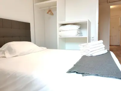 a bedroom with a bed with white sheets and towels at Céntrico apartamento in Barcelona