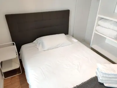 a small bedroom with a white bed with a black headboard at Céntrico apartamento in Barcelona