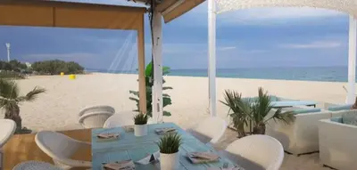 a table and chairs on the beach with the ocean at La Bellamar - Apartamento en primera línea mar- in Premiá de Mar
