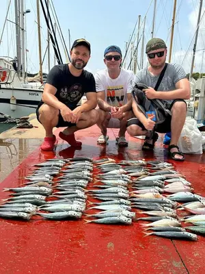 a group of three men kneeling next to a bunch of fish at Primera línea de mar y piscina a 20 minutos de Barcelona in Premiá de Mar