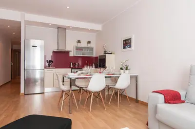 a kitchen with a table and white chairs in a room at Pelayo Deluxe Apartments in Barcelona
