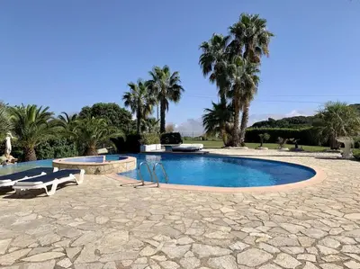 a swimming pool with two chairs and palm trees at Finca Montnegre Suites and Spa in Sant Iscle de Vallalta